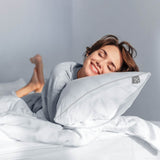 Glückliche Frau schläft auf dem smart® Soft Pillow in der Größe Large 80 x 80 cm, dem weichen nachhaltigen Kissen mit PrimaLoft Bio Füllung aus Recyclingfasern mit anpassbarer Kissenhöhe für einen hohen Schlaf-Komfort
